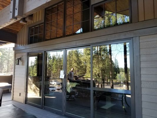 Clean sliding glass doors and upper clerestory windows reflecting pine forest views